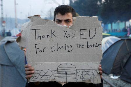 A refguee holds a message, "Thank you EU for closing the border" during a protest asking for the opening of borders at a makeshift camp at the Greek-Macedonian border near the village of Idomeni, Greece, March 18, 2016. REUTERS/Alkis Konstantinidis
