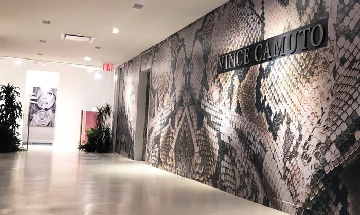Office with wall art and Vince Camuto logo.