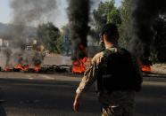 A Lebanese army soldier walks near burning tires during ongoing anti-government protests in Tripoli