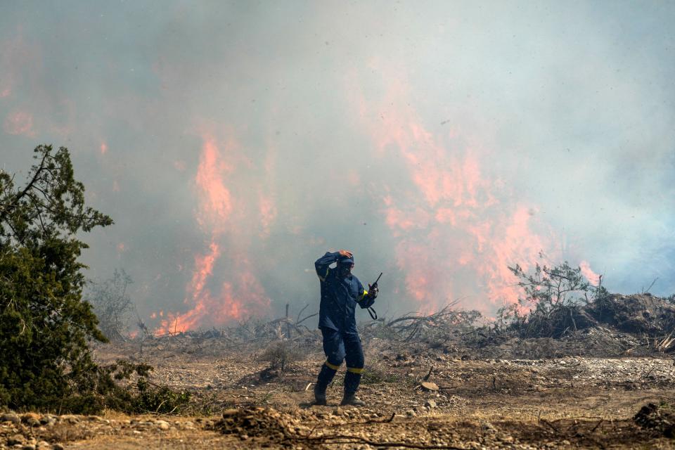 A firefighter operates as a wildfire burning a forest in Vati village, on the Aegean Sea island of Rhodes, southeastern Greece, on Tuesday, July 25, 2023. A third successive heat wave in Greece pushed temperatures back above 40 degrees Celsius (104 degrees Fahrenheit) across parts of the country Tuesday following more nighttime evacuations from fires that have raged out of control for days. (AP Photo/Petros Giannakouris)