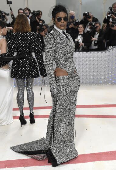 Teyana Taylor wears a sparkly silver gown, sunglasses and a fishnet veil on the Met Gala carpet