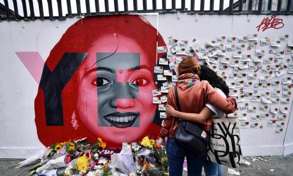 Two women look at written notes left on the Savita Halappanavar mural.=