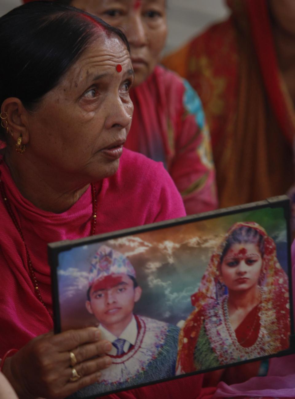 Indian woman Padma holds a photograph showing her son Bharat and daughter in law Partima with whom she has not been able to establish contact after Saturday's earthquake in Nepal, during a prayer ceremony for the earthquake affected at a Hindu temple in Jammu, India, Monday, April 27, 2015.  (AP Photo/Channi Anand)