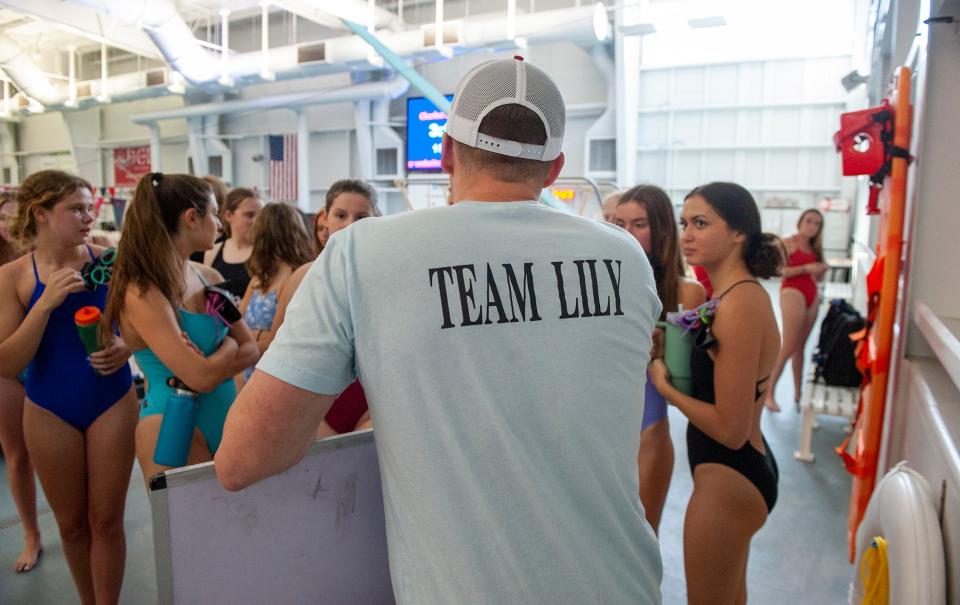 Wellesley High School girls swimming team coach Doug Curtin wears a "Team Lily" shirt at practice at the Boston Sports Institute, Oct. 4, 2023. Lily Kahrl, a Wellesley High School senior varsity swimmer, has a rare genetic disorder, STXBP1 encephalopathy. She competes in the 50-meter event.