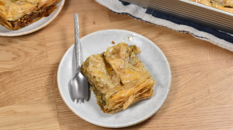 sliced baklava on white plate with metal spoon