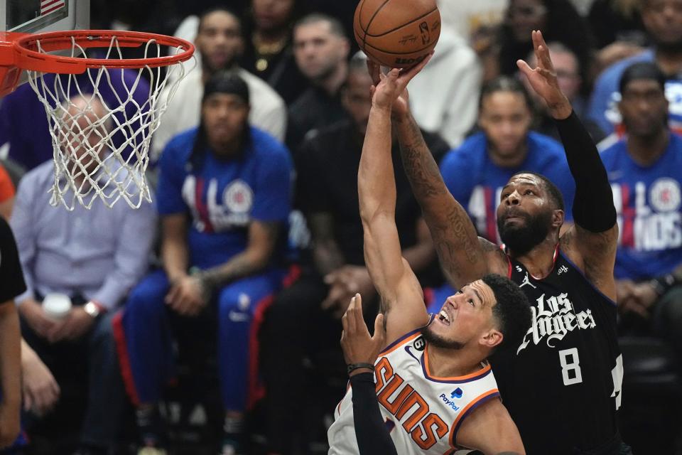 Phoenix Suns guard Devin Booker, left, shoots as Los Angeles Clippers forward Marcus Morris Sr. defends during the first half in Game 4 of a first-round NBA basketball playoff series Saturday, April 22, 2023, in Los Angeles. (AP Photo/Mark J. Terrill)