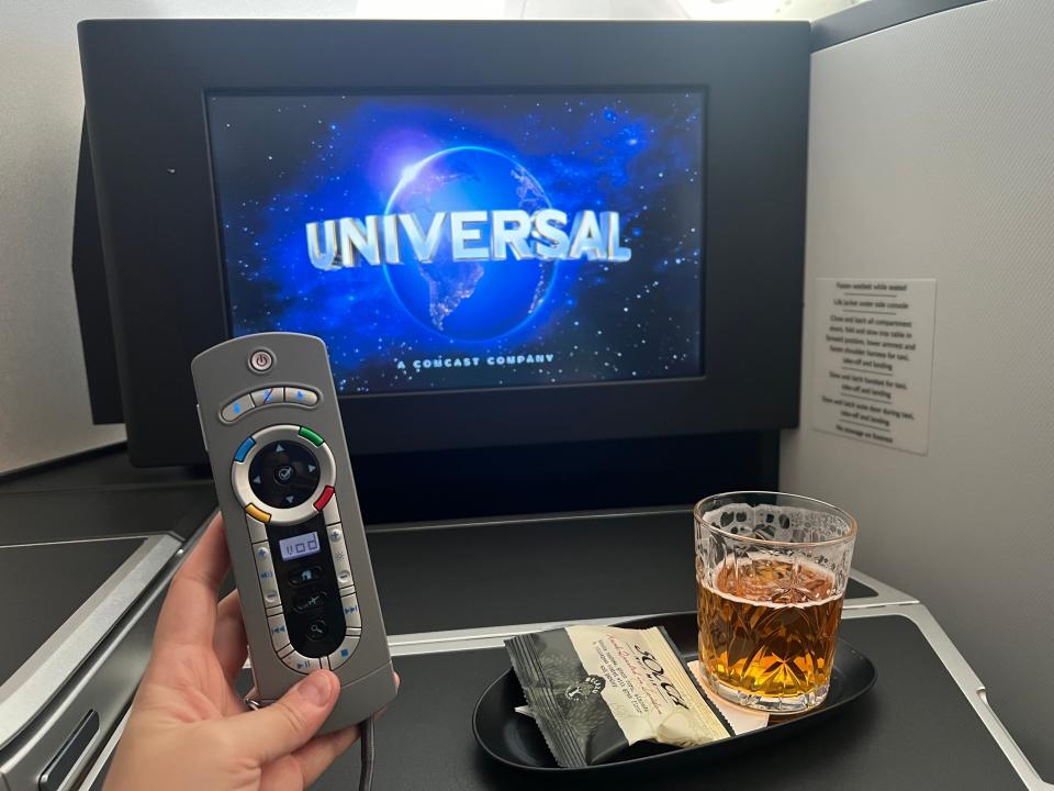 The author holding the remote with a beer on the tray table.