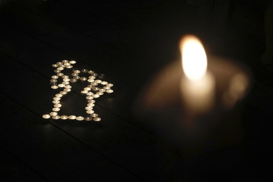 University students light candles to form a "Goddess of Democracy," left, at the site after the "Goddess of Democracy" statue, a memorial for those killed in the 1989 Tiananmen crackdown, was removed from the Chinese University of Hong Kong, Friday, Dec. 24, 2021. The university early Friday morning took down the statue that was based on a figure created by art students and brought to the square shortly before the crackdown in which hundreds of people were killed. (AP Photo/Vincent Yu)