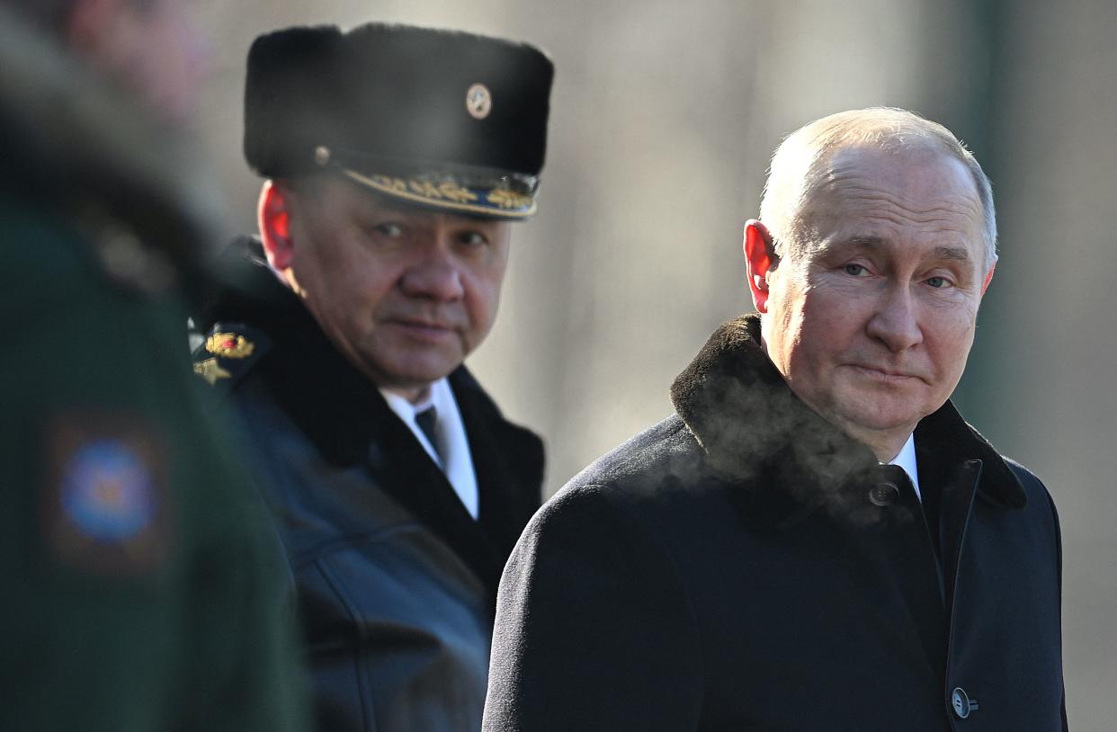 President Vladimir Putin, in a fur-collared coat and looking amused, with Defense Minister Sergei Shoigu in military uniform.