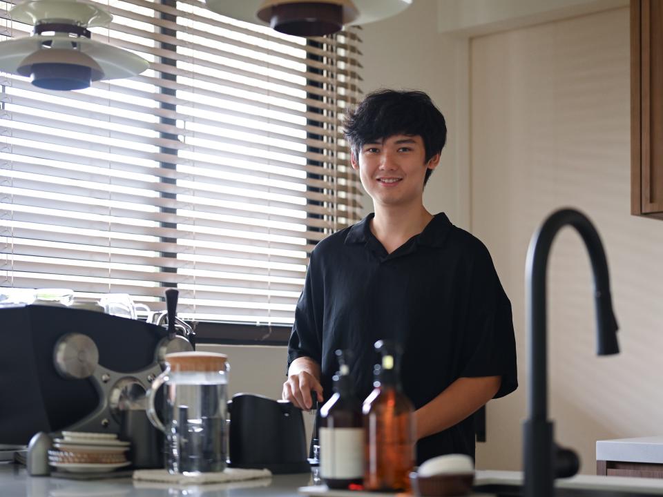 A young man standing behind a kitchen counter.