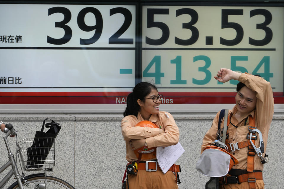 Workers wait to cross a street in front of an electronic stock board showing Japan's Nikkei 225 index at a securities firm Thursday, June 27, 2024 in Tokyo. (AP Photo/Shuji Kajiyama)