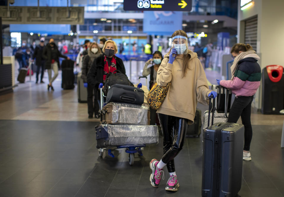 Passengers, wearing face masks to protect against coronavirus, wait in line for check-in, on their way to Frankfurt, at the Vilnius International Airport in Vilnius, Wednesday, May 13, 2020. Lithuania suspended flights due to the threat of coronavirus on April 4. The German airline Lufthansa has began flying from Vilnius to Frankfurt on Wednesday. The Lithuanian government extended the nationwide coronavirus quarantine until May 31. (AP Photo/Mindaugas Kulbis)