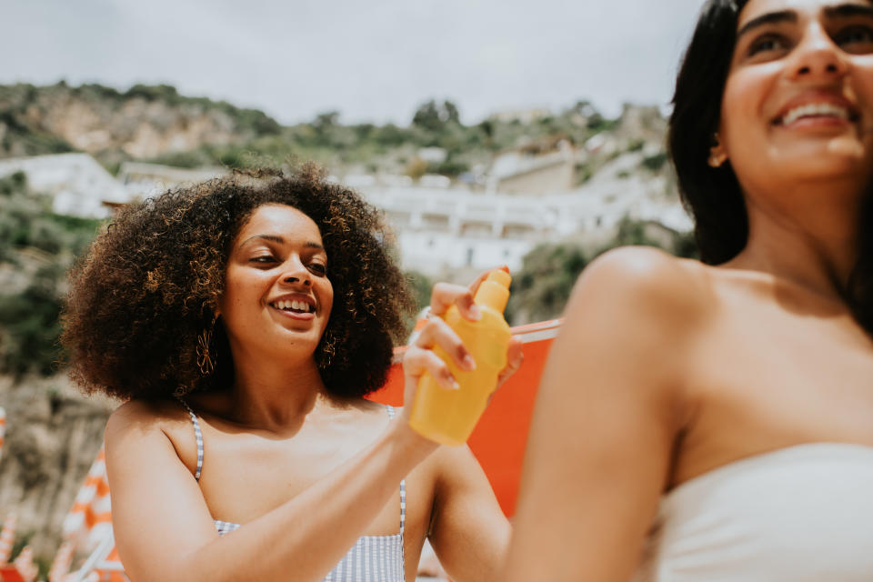 Two friends applying sunscreen outdoors, promoting skin health