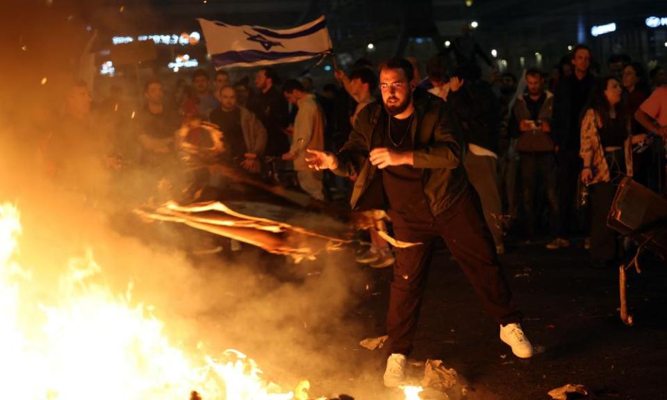 Protesters block a road and hold national flags as they gather around a bonfire during a rally against the Israeli government’s judicial reform in Tel Aviv, Israel