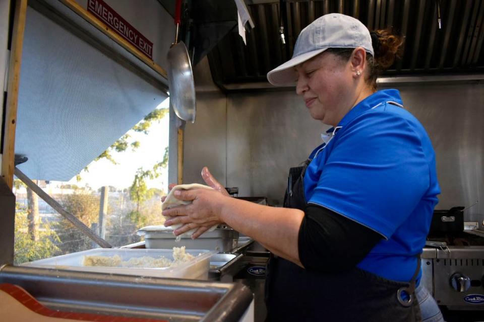 Digna Díaz, owner of Plátano, Pupusas Y Cafecito, rolls a pupusa stuffed with chicharron and cheese in her hands Oct. 7. Díaz learned to cook from her mother and has been making pupusas since she was 10 years old. She and her husband, Adonay Díaz, who fought in the Salvadoran Civil War, immigrated to the U.S. as refugees.
