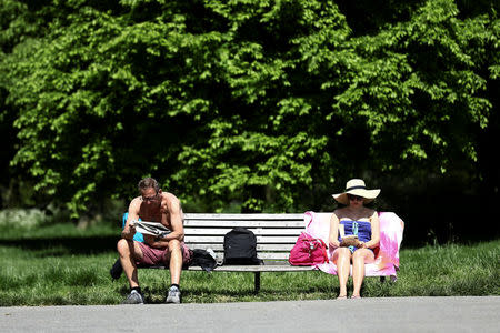 People read as they sit on a bench in hot weather on Primrose Hill in London, Britain May 7, 2018. REUTERS/Simon Dawson