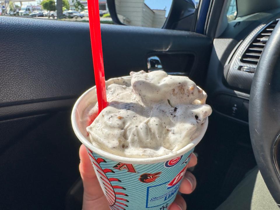 Oreo brookie blizzard with red spoon sticking out of it in a blue dairy queen cup in a car