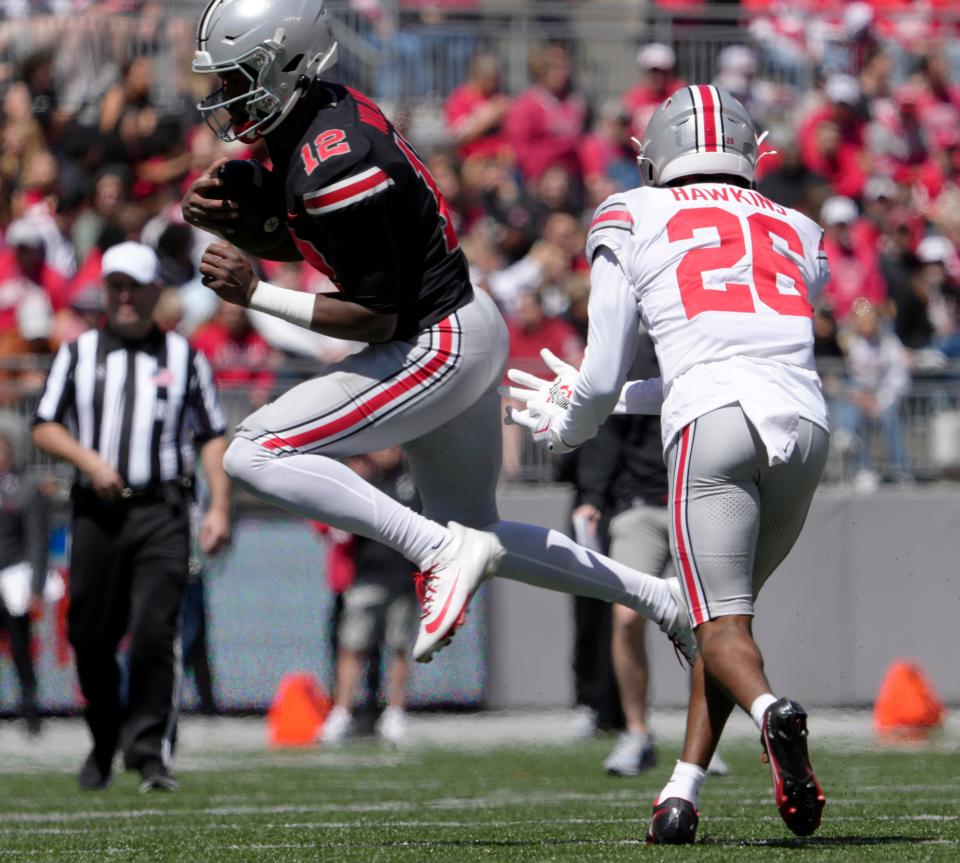 April 13, 2024; Columbus, Ohio, USA; 
Ohio State Buckeyes quarterback "Air" Noland (12) leaps away from safety Cedrick Hawkins Jr. (26) of the grey team during the second half of the LifeSports spring football game at Ohio Stadium on Saturday.