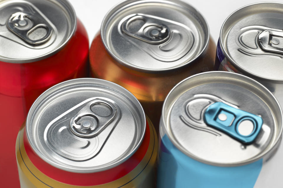 Cola soda fizzy drinks cans in a row on a white background