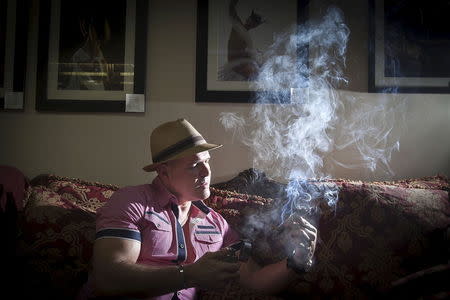 Owner of Guantanamera Cigars, Jose Montagne lights up a cigar as he poses for a photo in his store on the famed Calle Ocho (Eighth Street) in the Little Havana section of Miami, April 16, 2015. REUTERS/Carlo Allegri