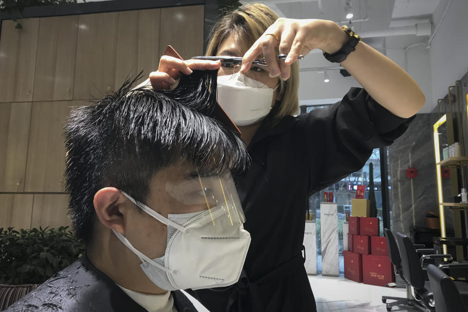 A barber wearing a protective face mask cuts a clients hair with an eye cover and face mask at a hair salon in Beijing, Monday, Feb. 24, 2020. Monday is the second day of the second month of the Chinese lunar calendar, traditionally an auspicious time when people rush into barbershops to get new haircuts. Getting a fresh look on the day is thought to bring good luck for the year ahead, but getting a haircut has become a challenge in China now that most barbershops are temporarily shut to avoid public gatherings amid the virus outbreak. (AP Photo/Olivia Zhang)