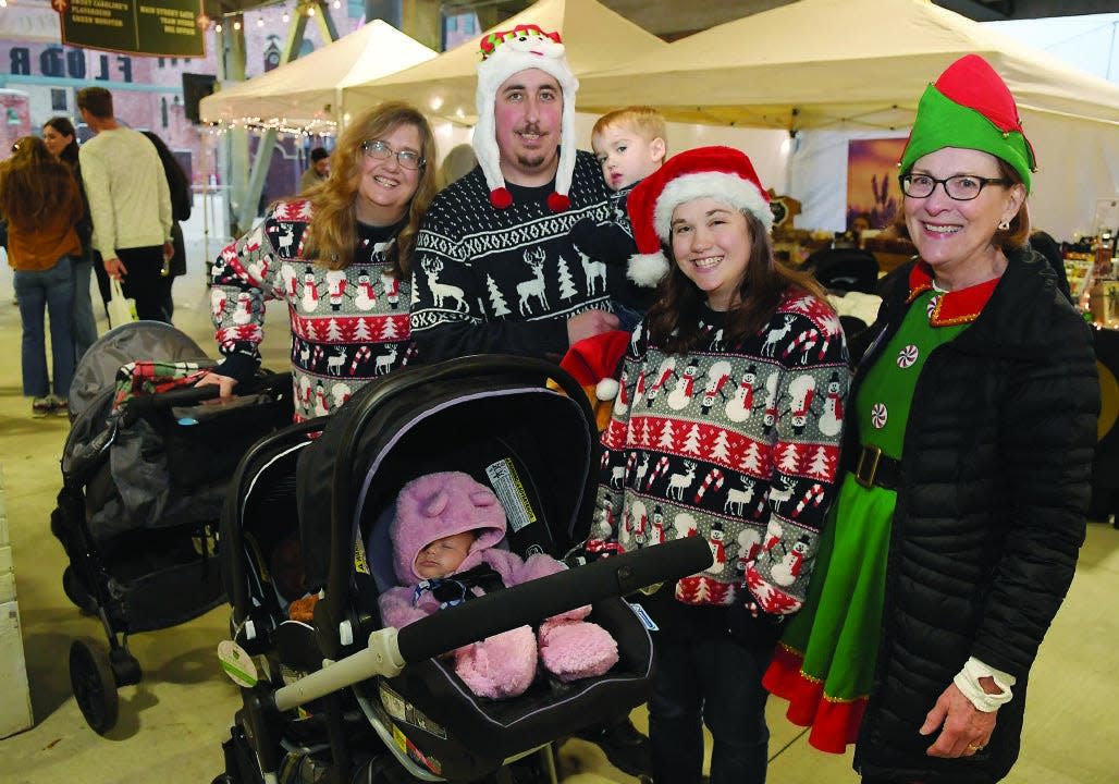 A family in festive outfits arrives at last year's Kringle Holiday Village at Fluor Field.
