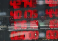 Turkish flags are reflected in the front window board of a currency exchange shop, showing current rates, in Istanbul, Wednesday, Aug. 15, 2018. The Turkish lira has nosedived in value in the past week over concerns about Turkey's President Recep Tayyip Erdogan's economic policies and after the United States slapped sanctions on Turkey angered by the continued detention of an American pastor. (AP Photo/Lefteris Pitarakis)