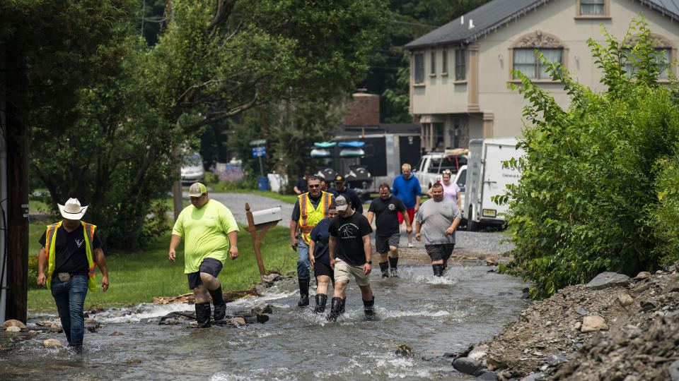 First responders and firefighters walk on water flowing along a roadway impacted by recent storms and flooding, Monday, July 17, 2023, in Belvidere, N.J. (AP Photo/Eduardo Munoz Alvarez)