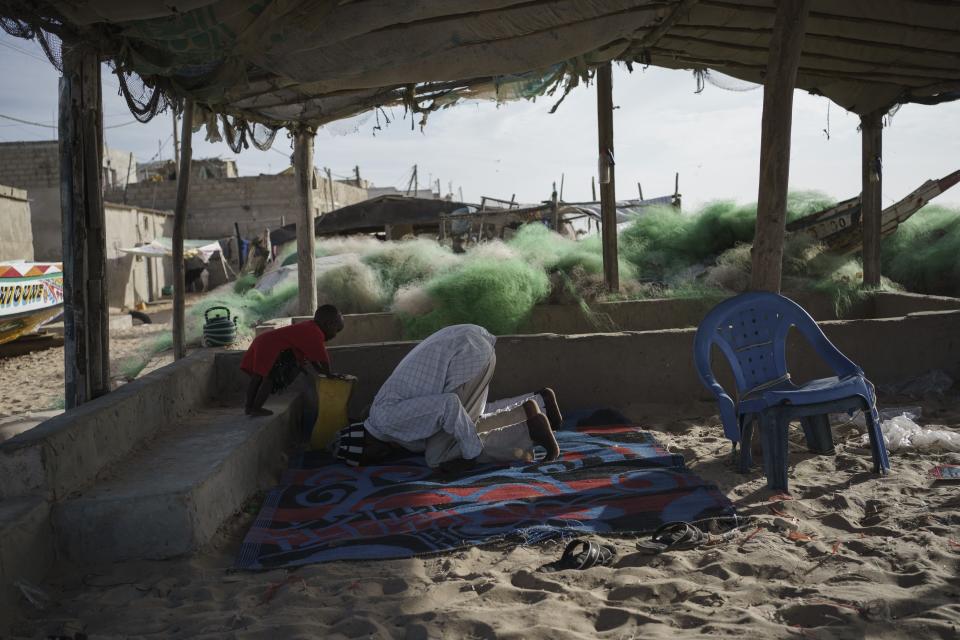 Fishermen pray at the beach during the evening in Saint Louis, Senegal, Tuesday, Jan. 17, 2023. Fishing has long been the community's lifeblood, but the industry was struggling with climate change and COVID-19. (AP Photo/Leo Correa)