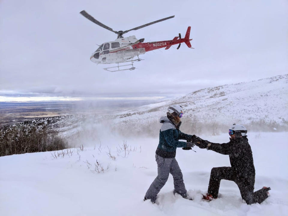 This Feb. 6, 2020 photo shows Jake Avery proposing to Kate Whiting while helicopter skiing in Nevada’s Ruby Mountains. The two had been planning a 300-person wedding but decided to marry June 6 in their Northern California backyard, with a big party after the coronavirus pandemic settles. They’re feeding a trend toward micro weddings that has grown stronger since the health crisis sent millions into isolation. (Mike Royer/Ruby Mountains Helicopter Experience via AP)