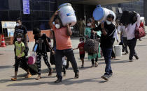 People wearing masks as a precaution against the coronavirus walk to board trains at Lokmanya Tilak Terminus in Mumbai, India, Friday, April 16, 2021. Migrant workers are swarming rail stations in India's financial capital Mumbai to go to their home villages as virus-control measures dry up work in the hard-hit region. The government of Maharashtra state imposed lockdown-like curbs on Wednesday for 15 days to check the spread of the virus. It closed most industries, businesses and public places and limited the movement of people, but didn’t stop the bus, train and air services. An exodus ensued, with panicked day laborers hauling backpacks onto overcrowded trains leaving Mumbai, travel that raises fears of infections spreading in rural areas. (AP Photo/Rajanish Kakade)