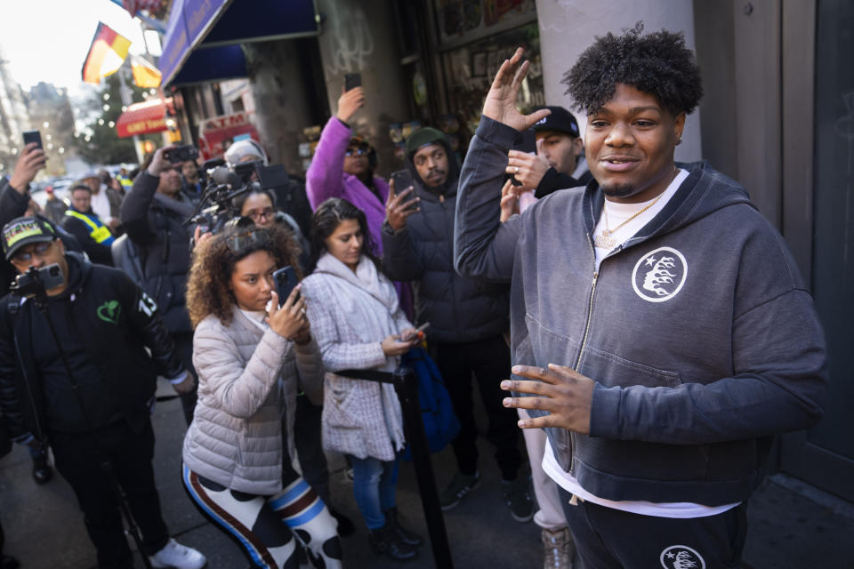 Darius Conner, son of business owner Roland, speaks to waiting customers and media members outside the Smacked "pop up" cannabis dispensary location they operate, Tuesday, Jan. 24, 2023, in New York. The store is the first Conditional Adult-Use Retail Dispensary (CAURD) opening since the legalization of cannabis that is run by businesspeople who had been criminalized by cannabis prohibition. (AP Photo/John Minchillo)