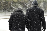 A couple walk through falling snow, Thursday, Feb. 18, 2021, in downtown San Antonio. Snow, ice and sub-freezing weather continue to wreak havoc on the state's power grid and utilities. (AP Photo/Eric Gay)