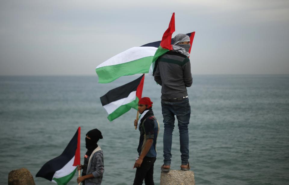 Palestinians wave national flags during a protest against the blockade on Gaza, at the seaport of Gaza City