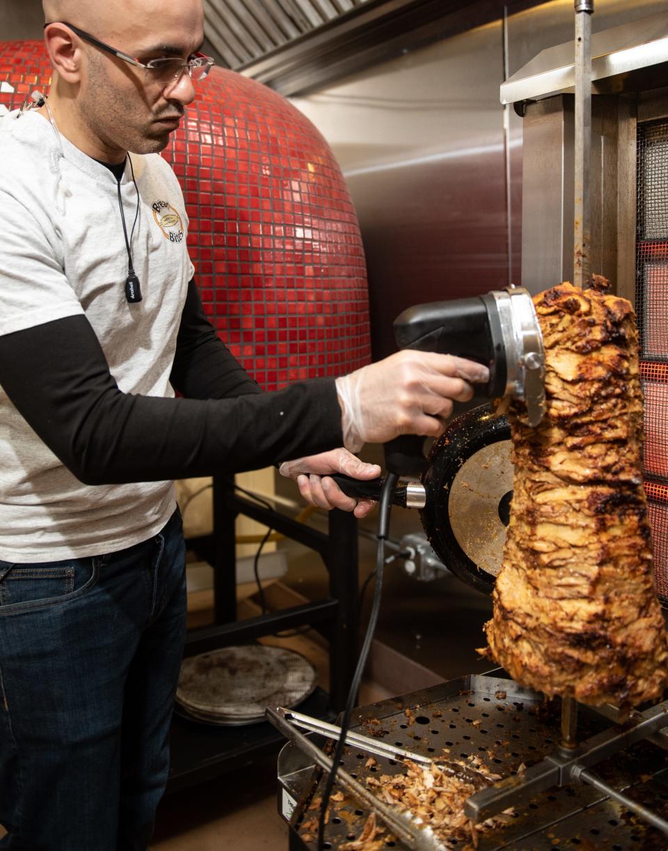 Rae Suboh, owner of Bread Bites in Okemos, trims slices of shawarma meat from the rotisserie Wednesday, Jan. 8, 2020.