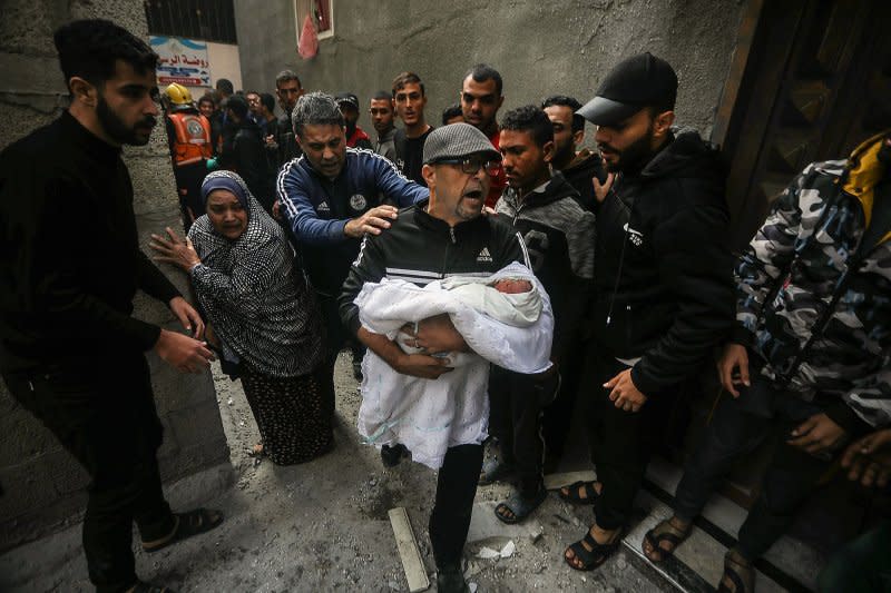 Palestinians carry a baby found alive following the resumption of Israeli bombing raids on houses in Rafah in southern Gaza on Friday. On Monday, U.N. officials called on Israel to avoid civilian casualties in its war. Photo by Ismael Mohamad/UPI