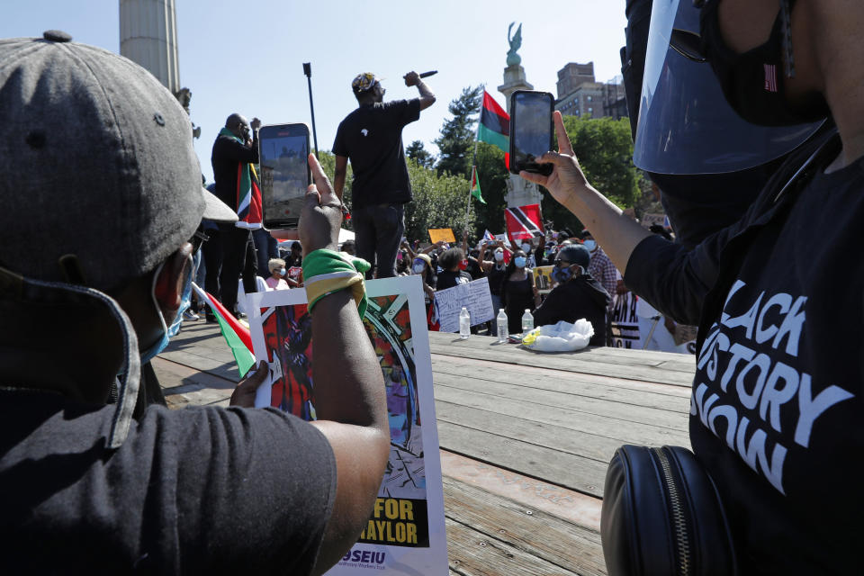 Two women use their cell phones to record a speaker during a Caribbean-led Black Lives Matter rally at Brooklyn's Grand Army Plaza, Sunday, June 14, 2020, in New York. A video of George Floyd's death went viral following the incident, capturing the world's attention. (AP Photo/Kathy Willens)