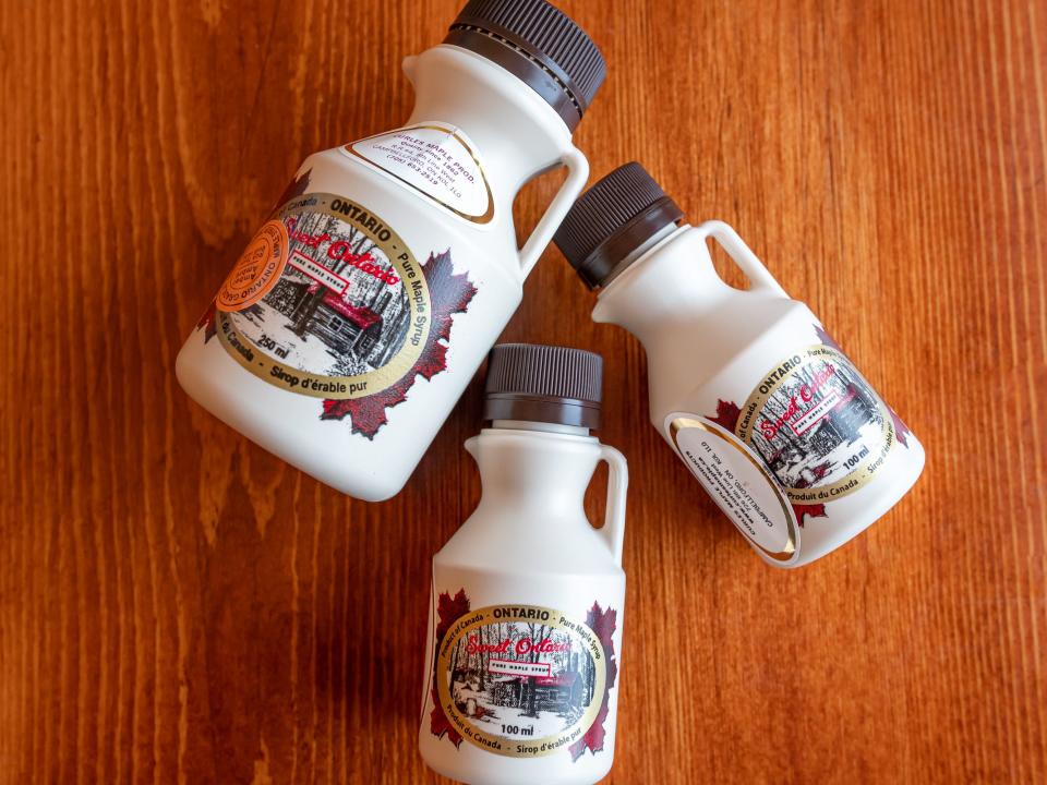 Three jugs of maple syrup on a wooden floor