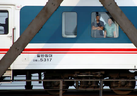 Men look out of a the window of a train that travels across Friendship Bridge from North Korea to China's Dandong, Liaoning province, September 12, 2016. REUTERS/Thomas Peter