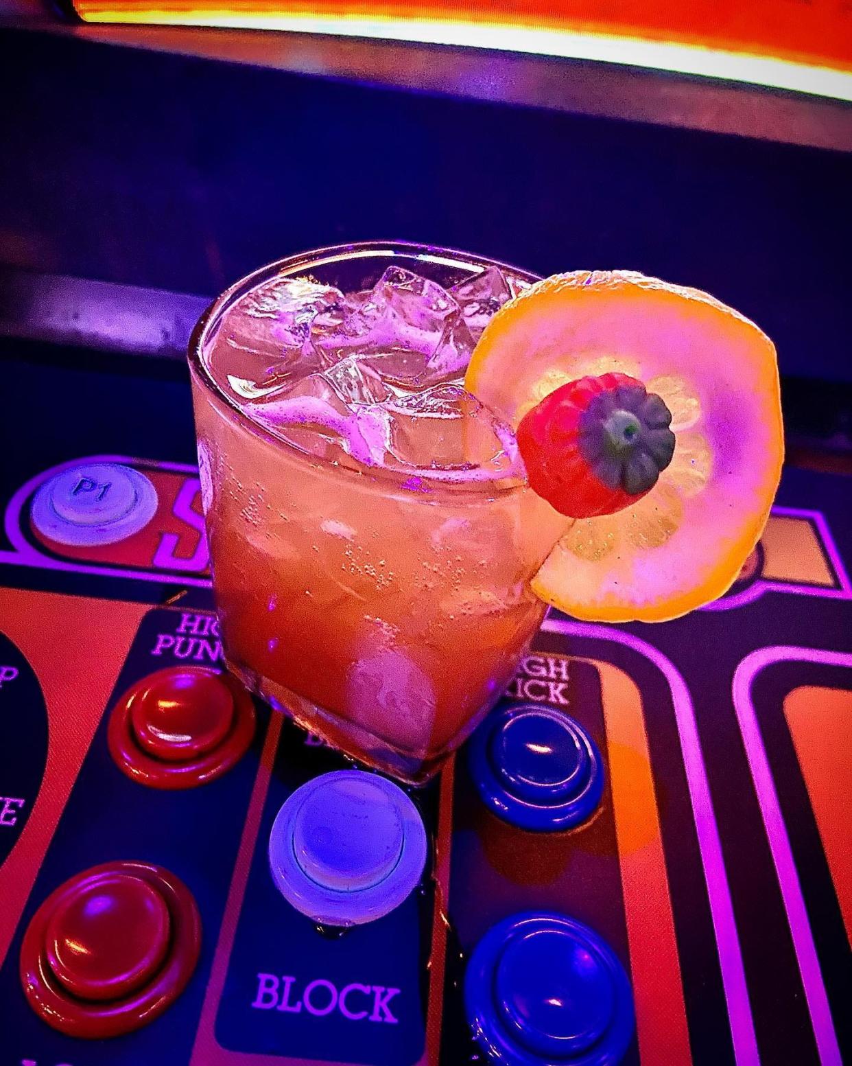 Play Arcade's Children of the Korn cocktail is a Candy-Corn Infused Vodka, lemon juice, cinnamon simple syrup, soda, and a candy pumpkin on the rocks.