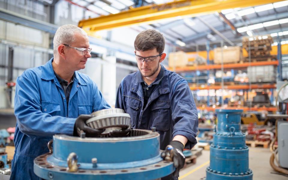 Engineer and apprentice installing bearings into pump house in electrical engineering factory