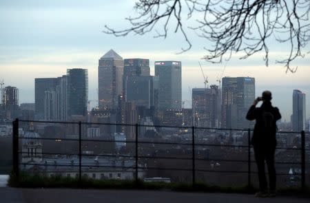 FILE PHOTO: A man takes a photograph of the Canary Wharf financial district from Greenwich Park in London, Britain, January 22, 2017. REUTERS/Hannah McKay/File Photo