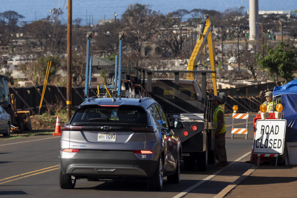 A member of the National Guard talks to a driver at a checkpoint on Lahainaluna Road, Wednesday, Dec. 6, 2023, in Lahaina, Hawaii. Recovery efforts continue after the August wildfire that swept through the Lahaina community on Hawaiian island of Maui, the deadliest U.S. wildfire in more than a century. (AP Photo/Lindsey Wasson)