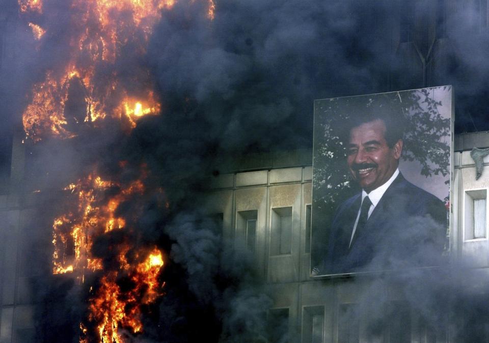 FILE - A portrait of Saddam Hussein still hangs on the burning Ministry of Transport and Communication building in Baghdad, April 9, 2003. Thousands went on a looting rampage as U.S. troops moved into the Iraqi capital. (AP Photo/Jerome Delay, File)