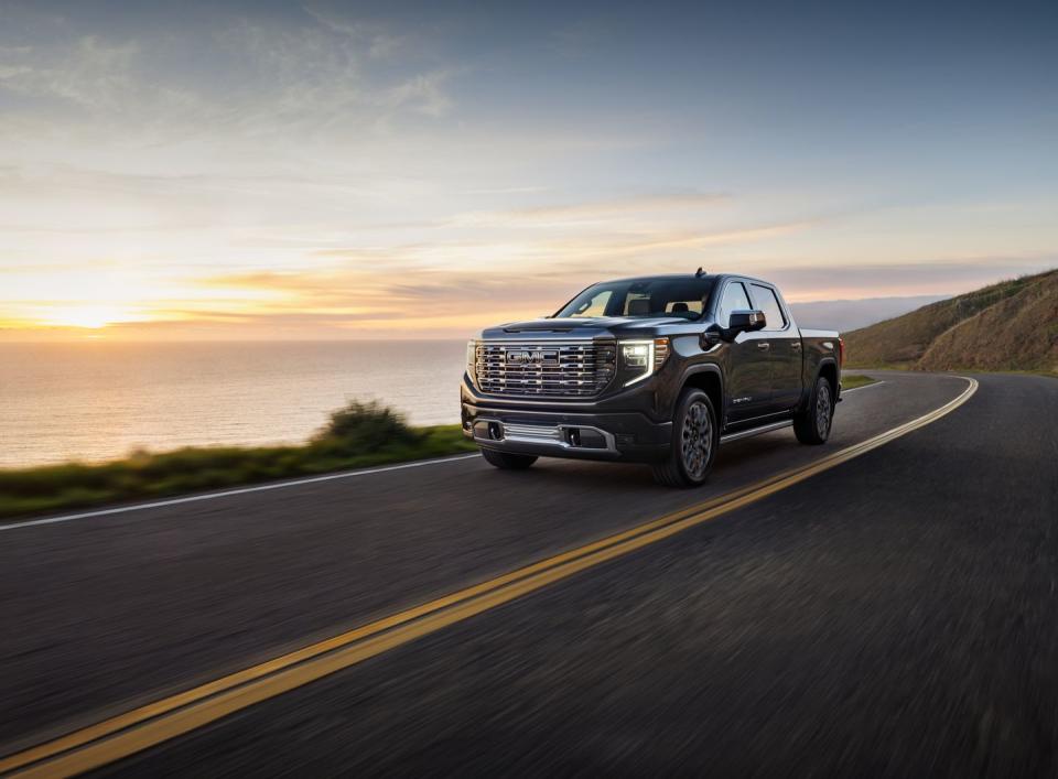 2024 gmc sierra denali ultimate 1500 crew cab short box in titanium rush metallic with 7 spoke ultra bright machined wheels 34 driver side front view in motion next to water