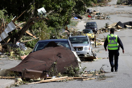 A police officer walks past damaged vehicles after a tornado hit the Mont-Bleu neighbourhood in Gatineau, Quebec, Canada, September 22, 2018. REUTERS/Chris Wattie