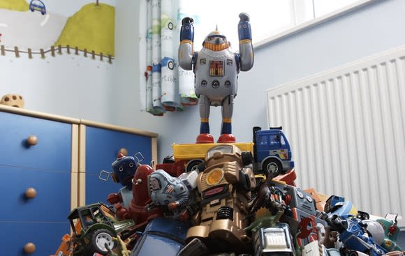 A toy robot on top of a pile of other toys.