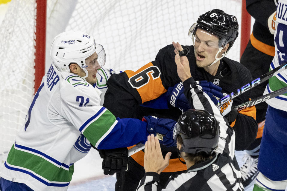 Vancouver Canucks left wing Nils Hoglander (21) and Philadelphia Flyers defenseman Travis Sanheim (6) fight during the second period of an NHL hockey game, Saturday, Oct. 15, 2022, in Philadelphia. (AP Photo/Laurence Kesterson)