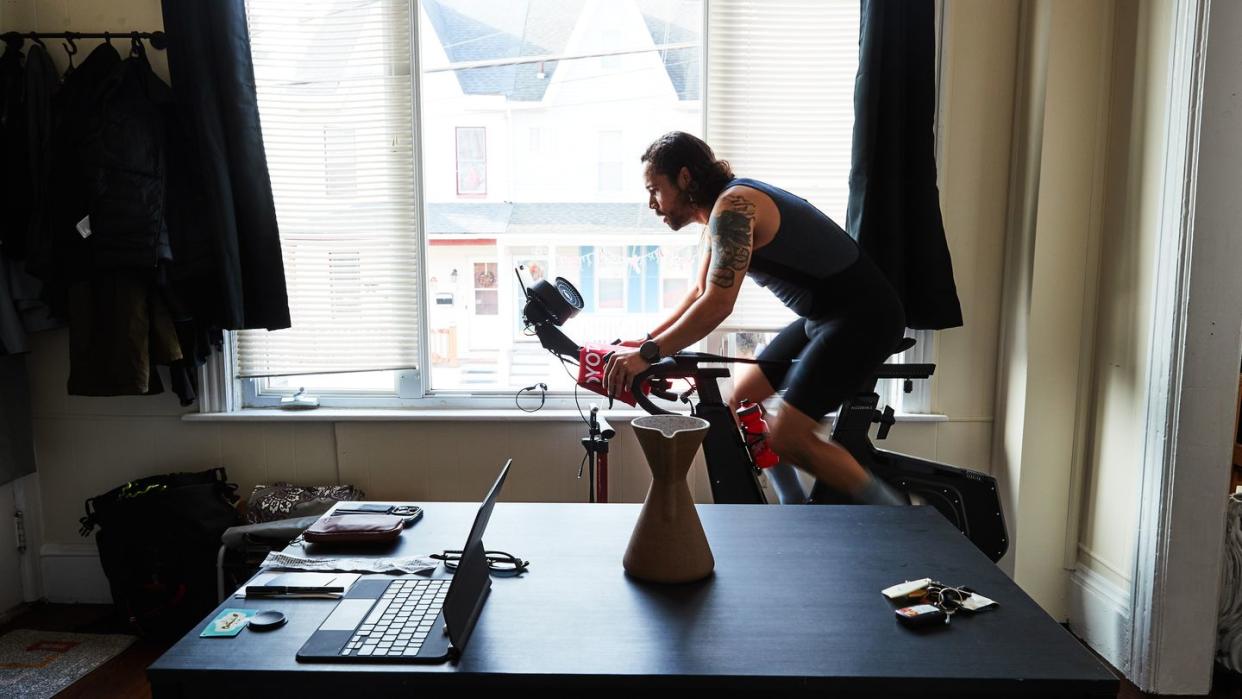 a man rides an stationary bike in front of a large window