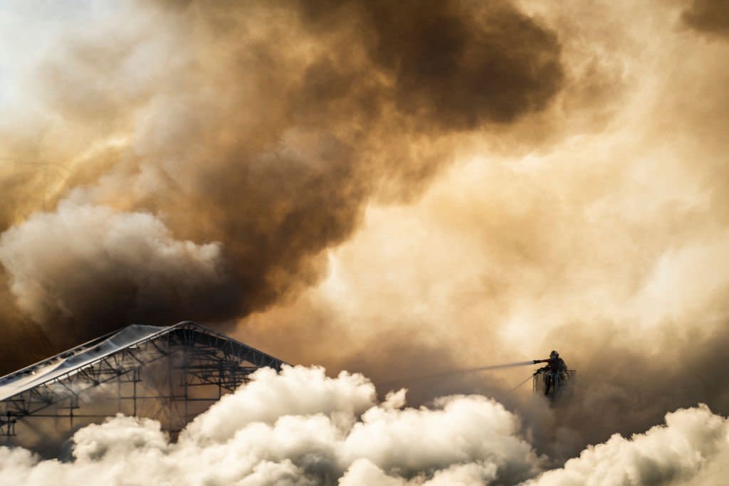 A firefighter tries to extinguish the flames as plumes of smoke billow from the historic Boersen stock exchange building in Copenhagen, Denmark